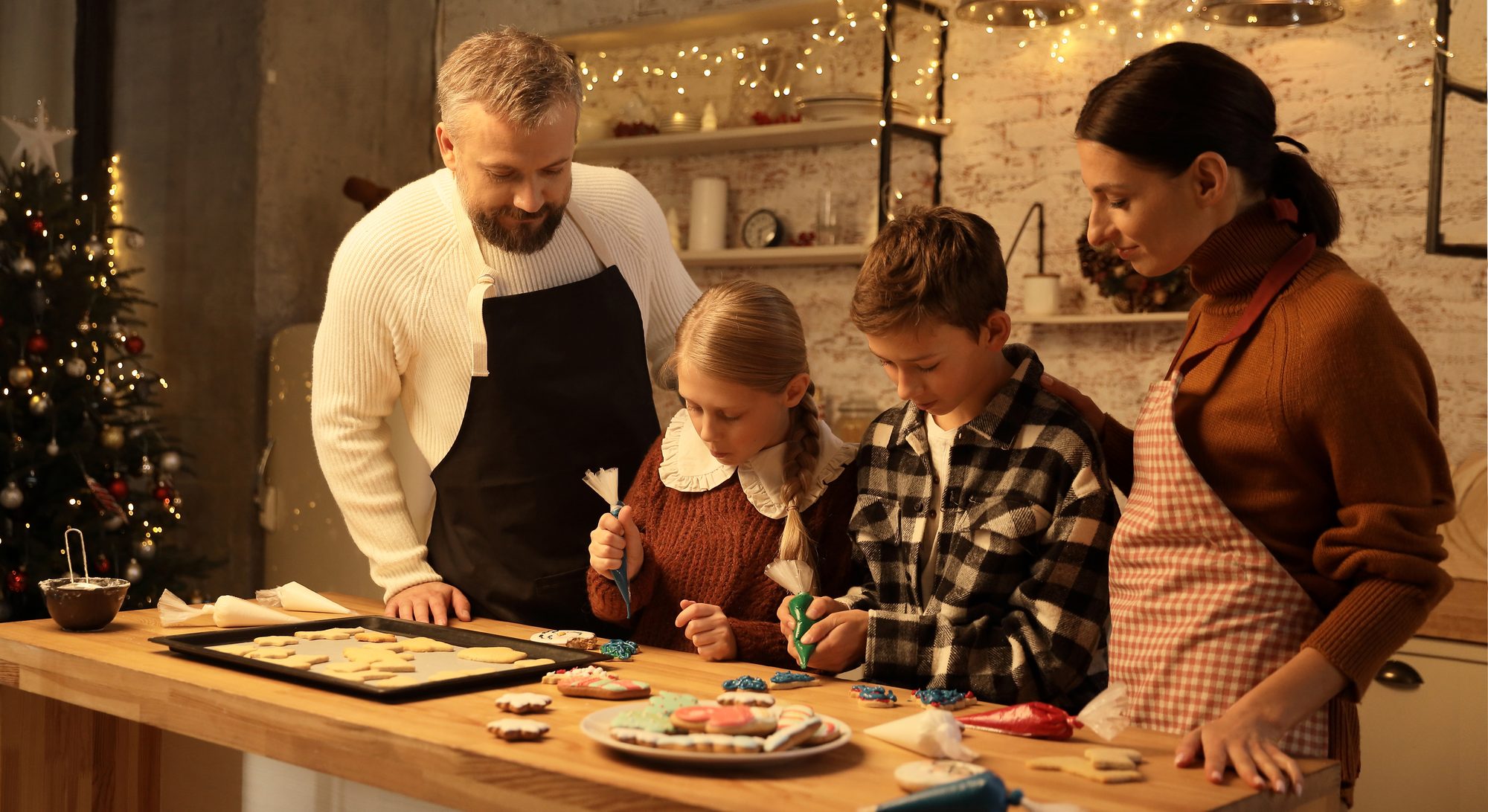 A family decorating cookies in a warmly lit kitchen
